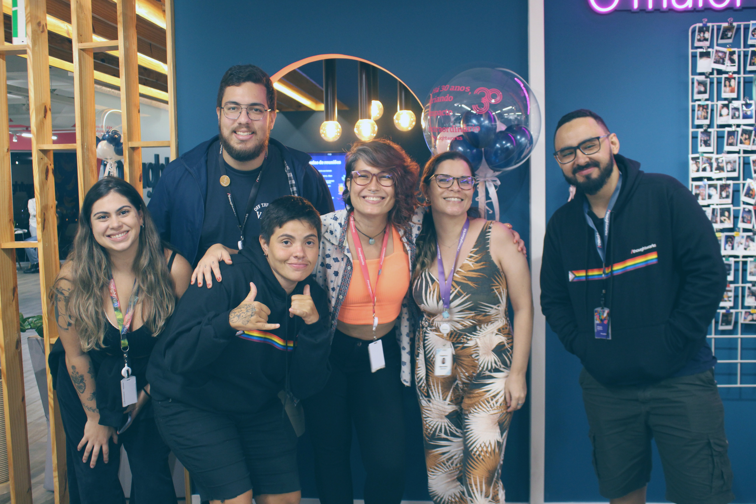 A group of 6 Thoughtworkers gathered and smiling for the photo, with the backdrop being the Thoughtworks office in Recife.