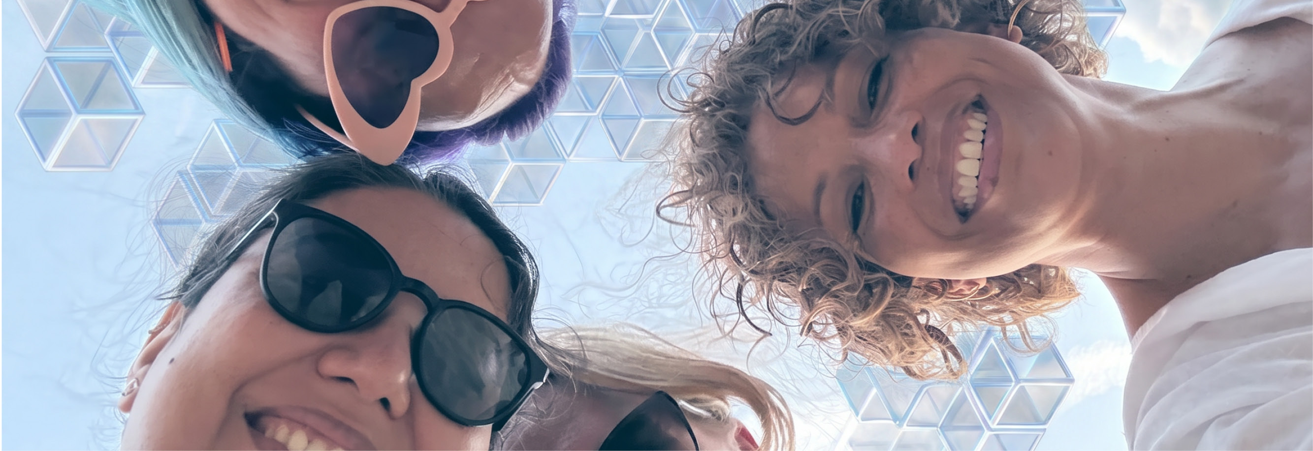A fun team shot - everyone is in a circle looking down at the camera, smiling with the sky behind them made of AI cubes