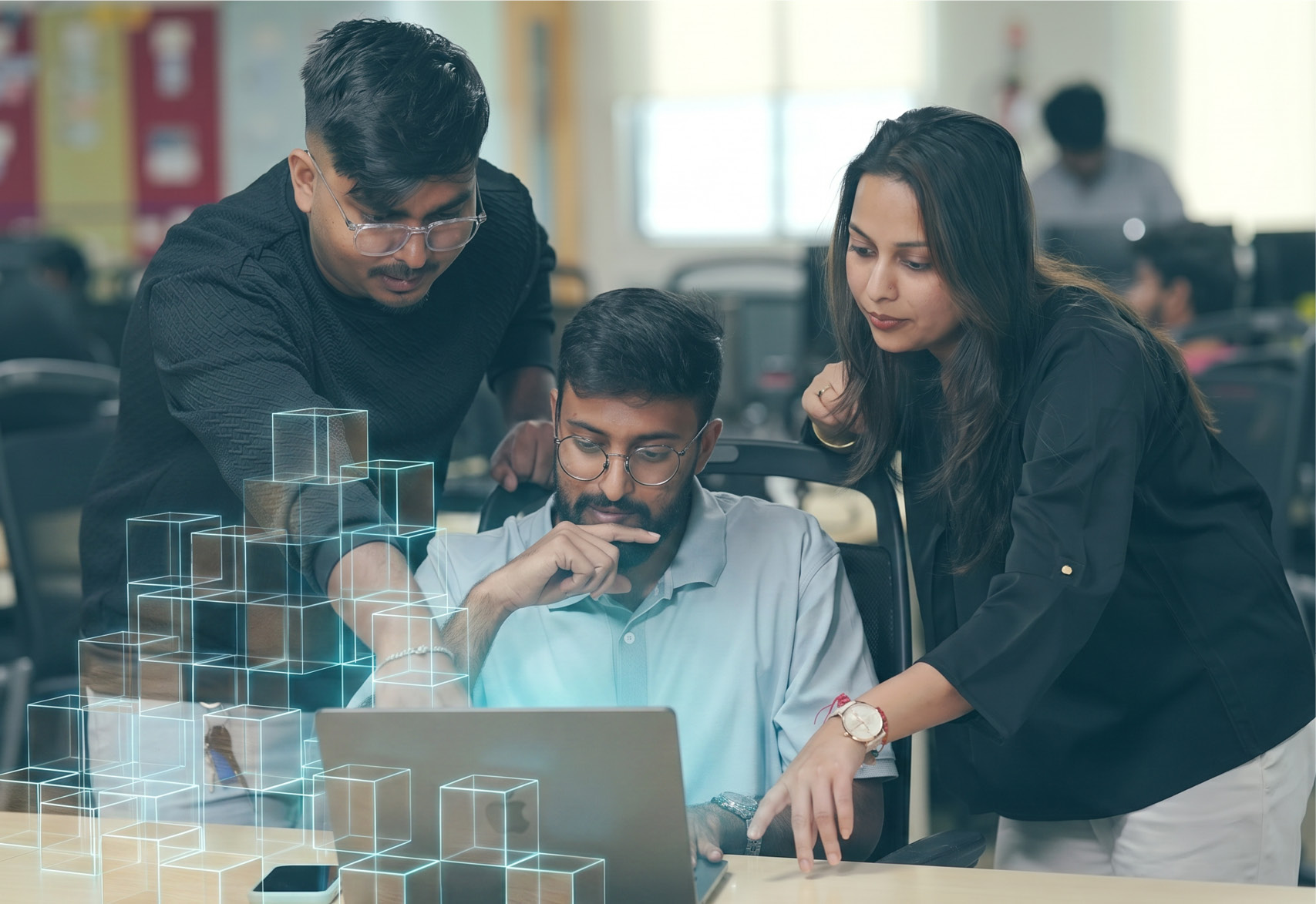 Three Thoughtworkers chatting around a laptop. All have dark hair, and are wearing casual clothes - AI cubes are dancing around the laptop.