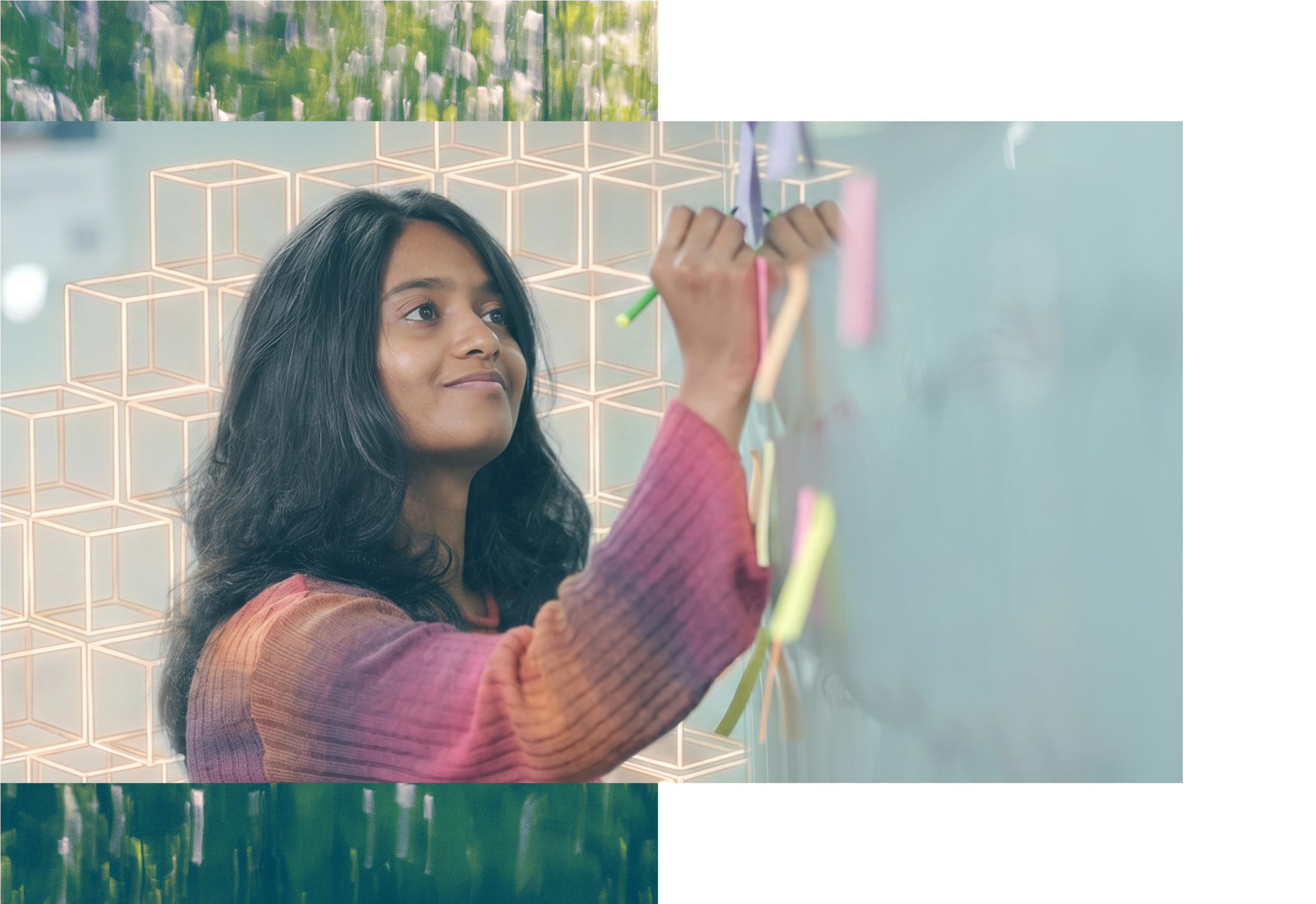 Wearing a multicoloured top, this Thoughtworker is smiling to herself while she writes on a sticky on the wall. AI cubes are in the background.