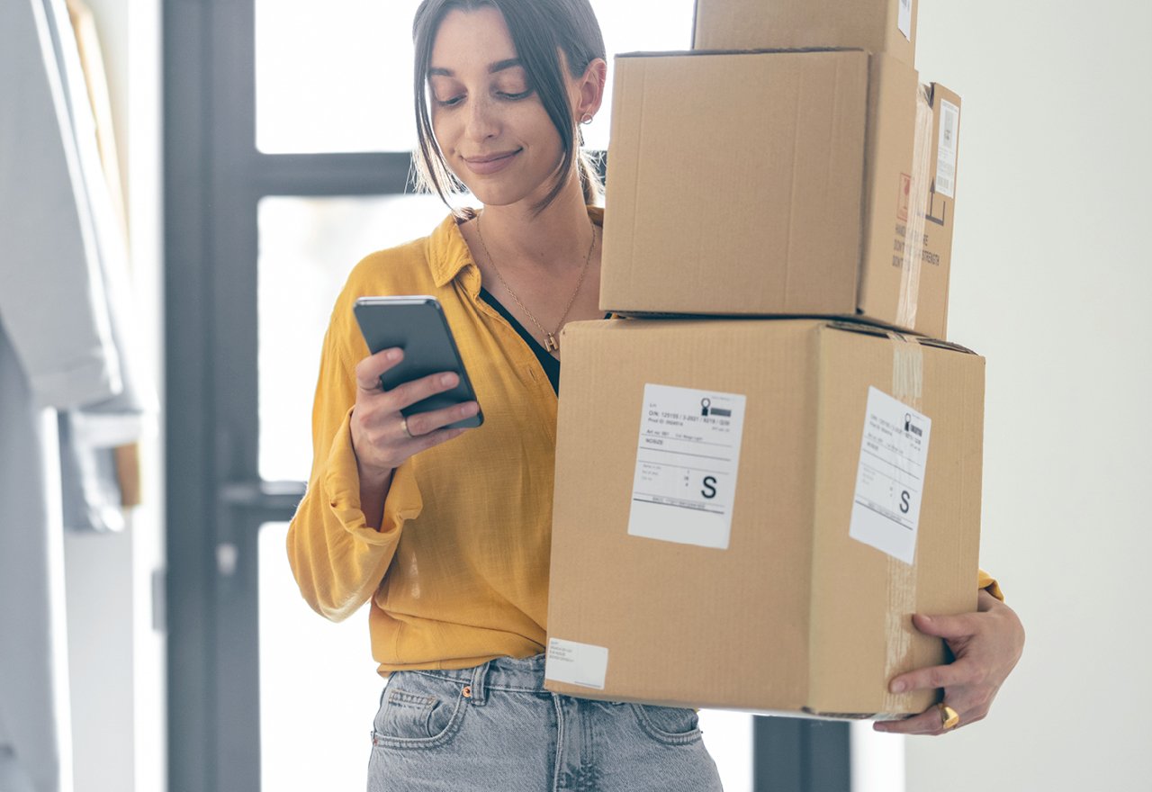 A consumer checks her phone while carrying her deliveries