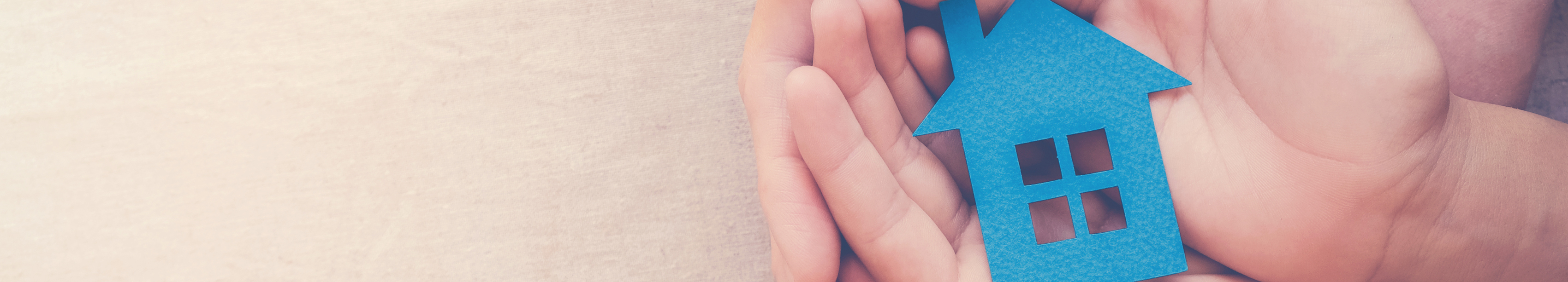 A parent and their childs hands holding a paper cut out of a house