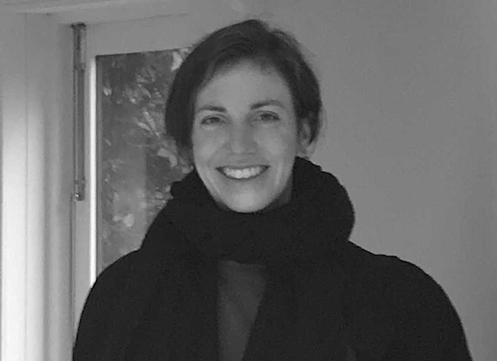 Black and white photo of Jeantine, wearing a scarf and smiling. Black and white photo of Jeantine, wearing a scarf and smiling.