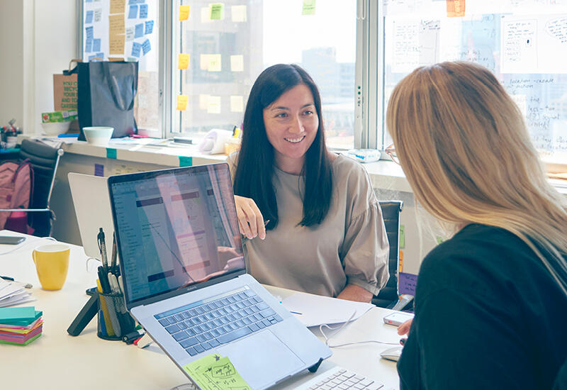 Two women collaborating around a laptop