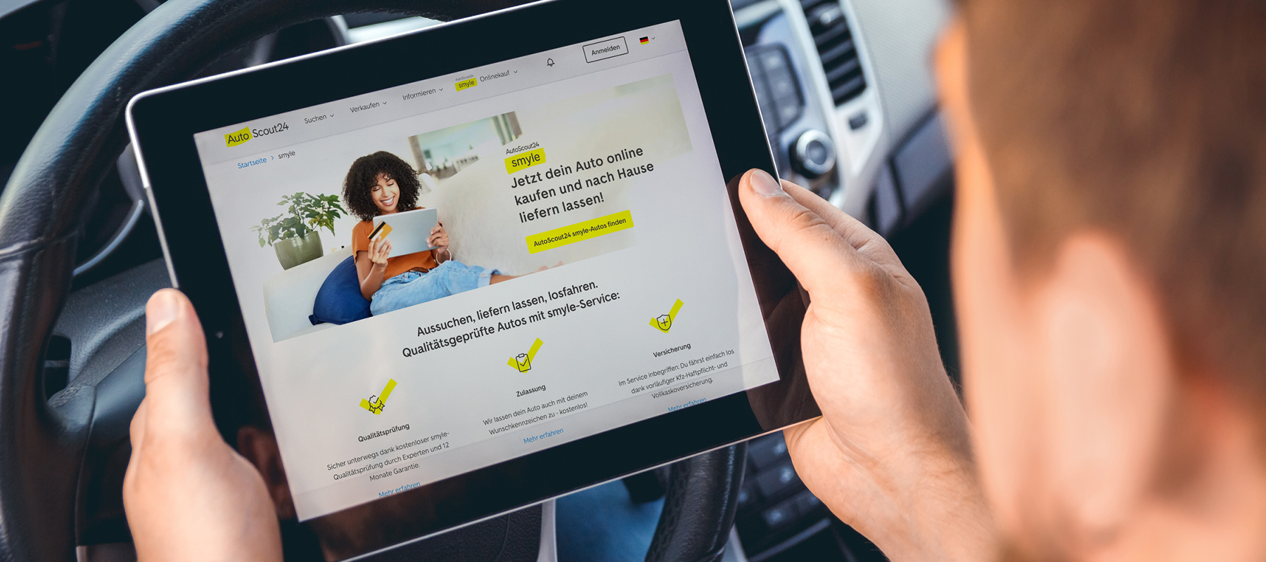 eine person hält ein tablet in der hand, im auto sitzen und schaut sich die website des Autoscout24 marketplace an
