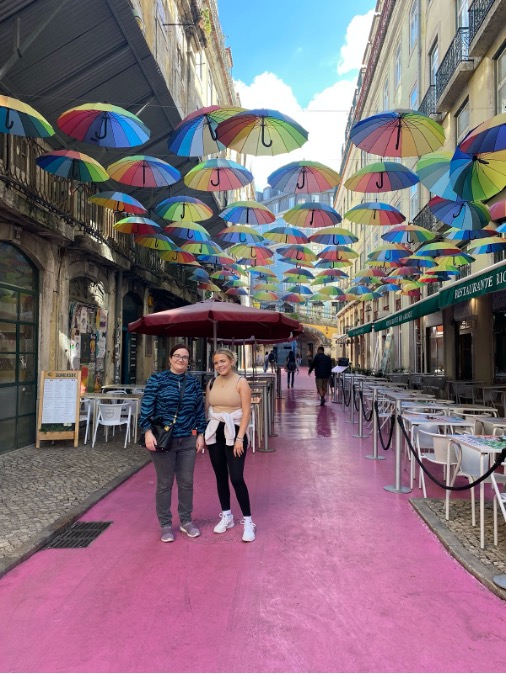 Image of Ella and Marghaid stood on a street in Lisbon. The street has decorative umbrellas.