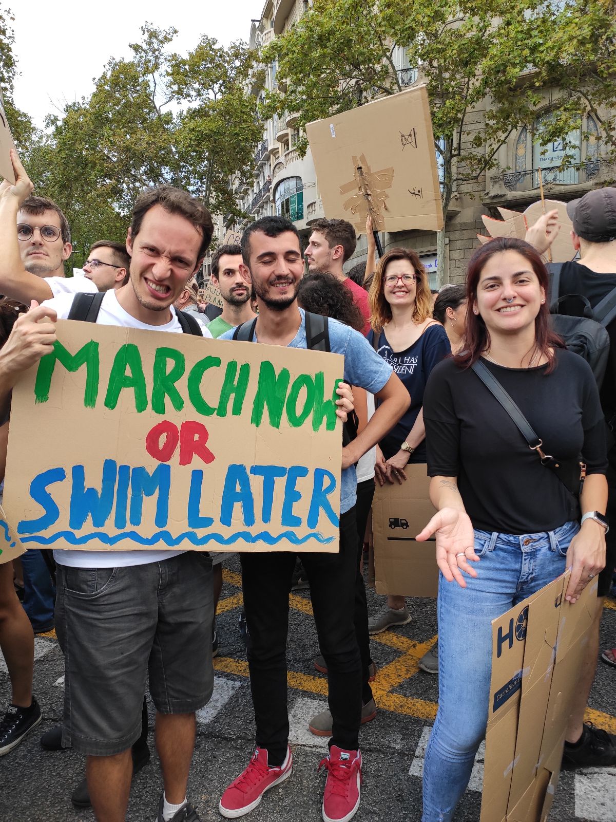 Image of protestors holding signs that say March now or swim later and No es el cuma es el capitalisme