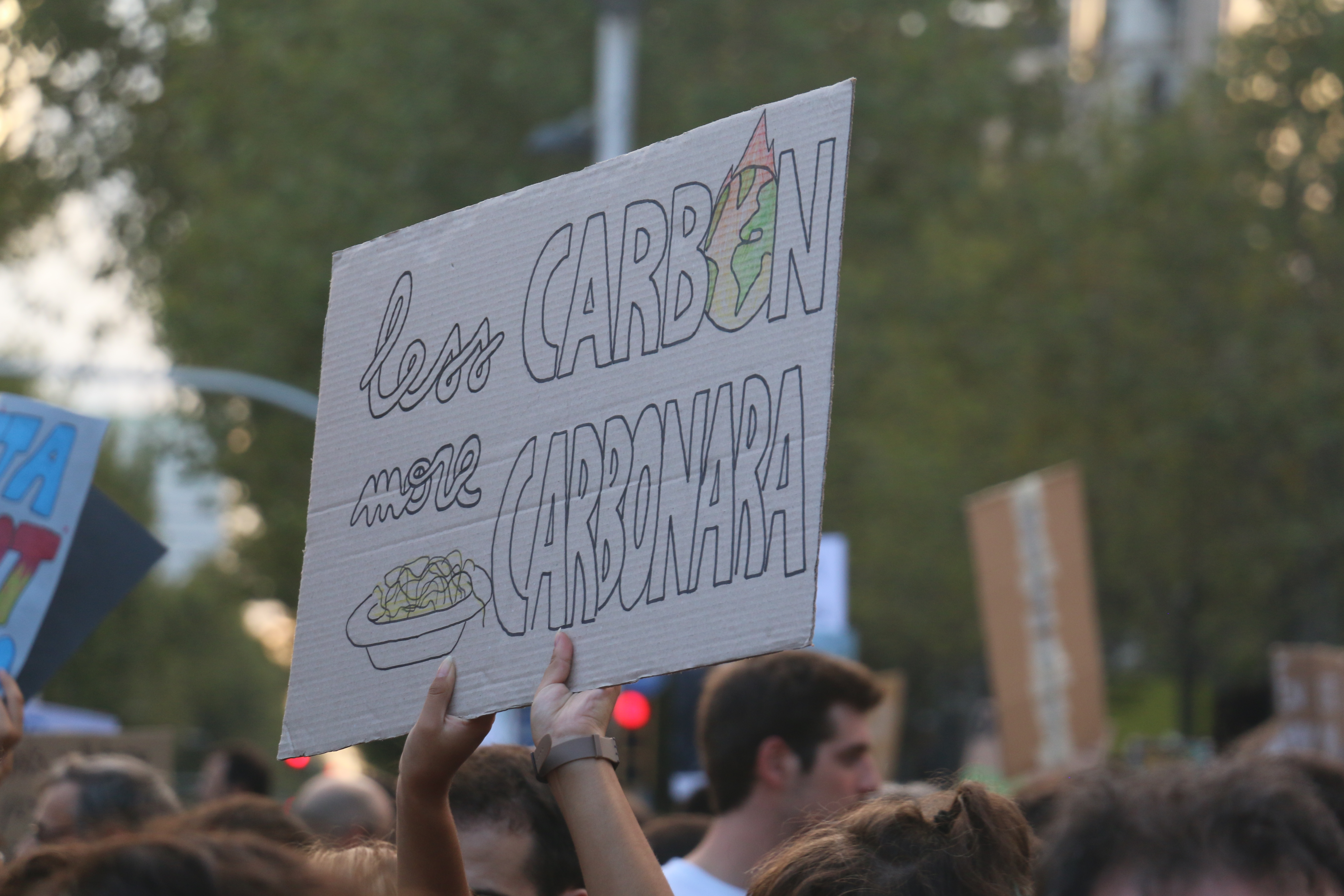 People holding a sign saying less carbon more carbonara