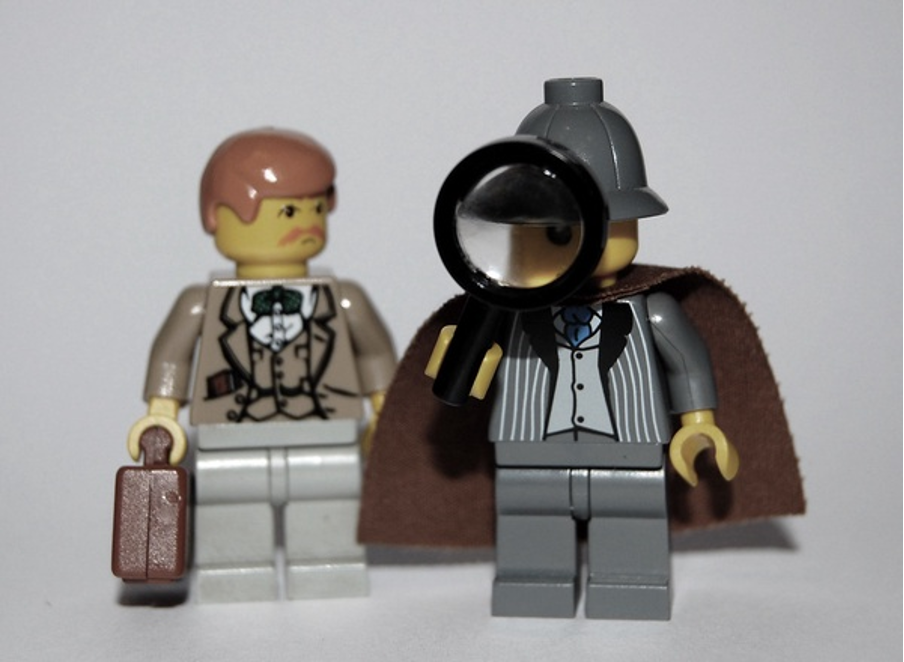Image of two lego people. One has a magnifying glass. 