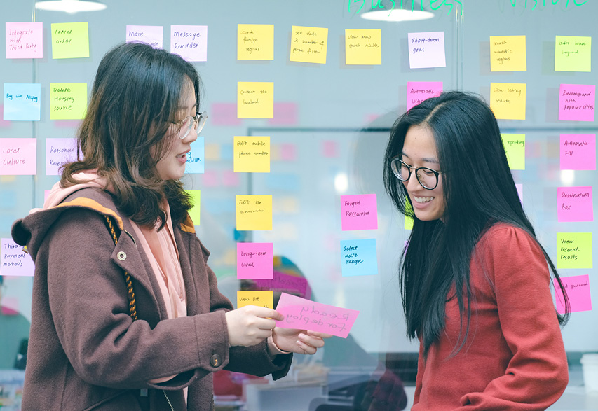 Thoughtworkers in China, discussing a story card with their project wall in the background