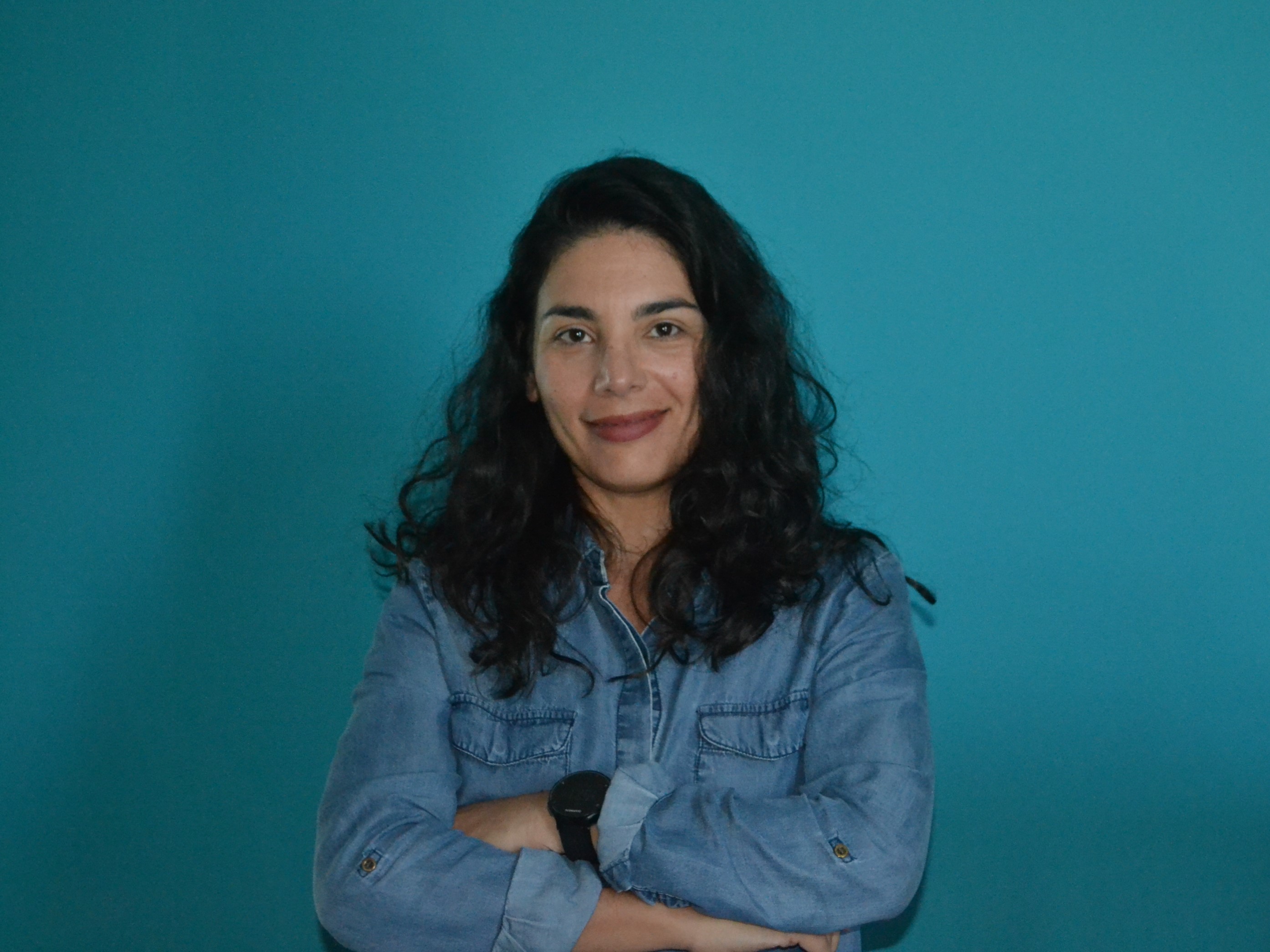 Image of Daniele standing in front of a blue wall