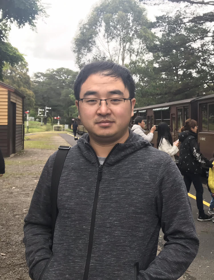 A picture of Jianxun Ma smiling and wearing a grey hoodie.