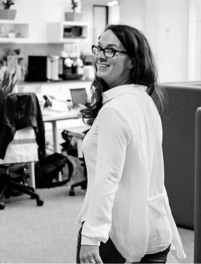 Katy - a white woman with long dark hair, walking through the London office Katy - a white woman with long dark hair, walking through the London office