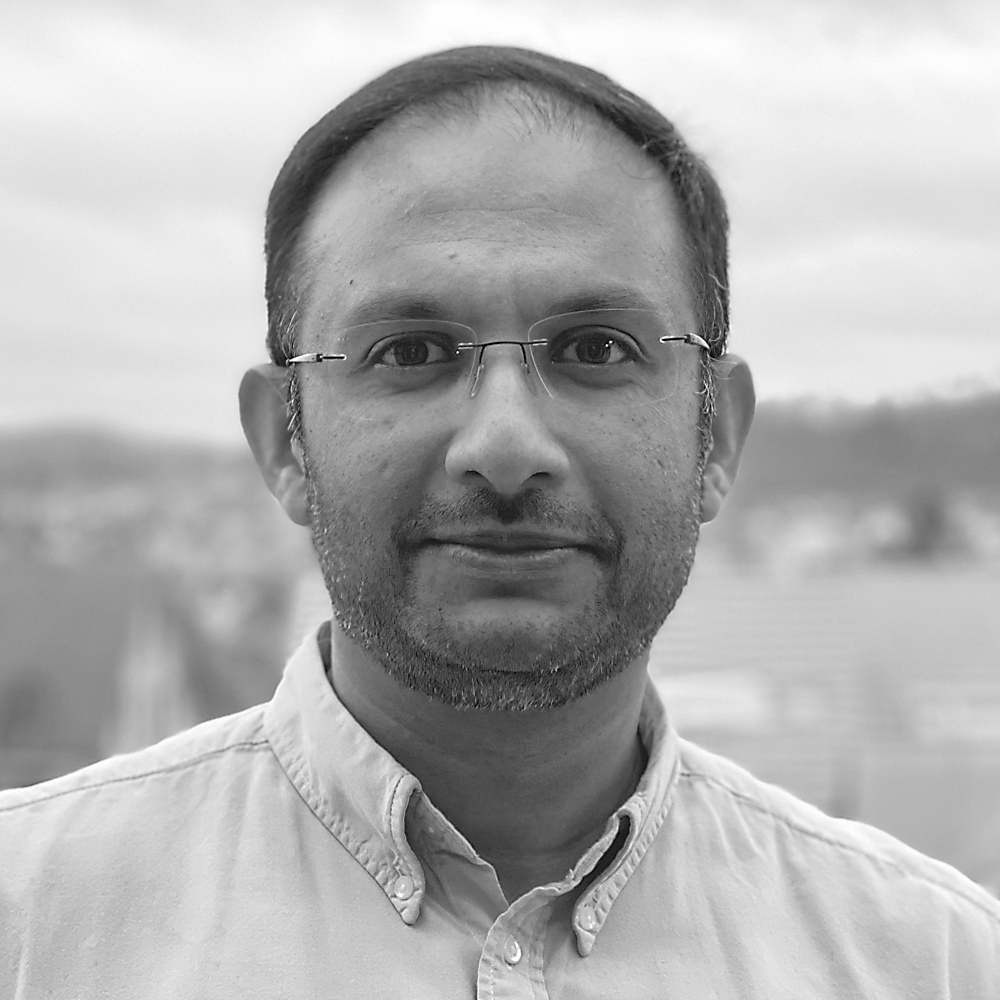 Omar Khawaja wearing glasses, very short beard and a button-down oxford.