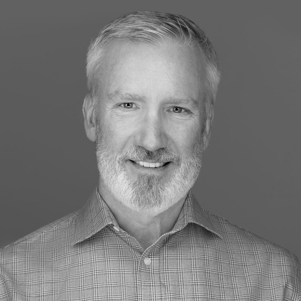 John Spens wearing a plaid button-down and white beard.