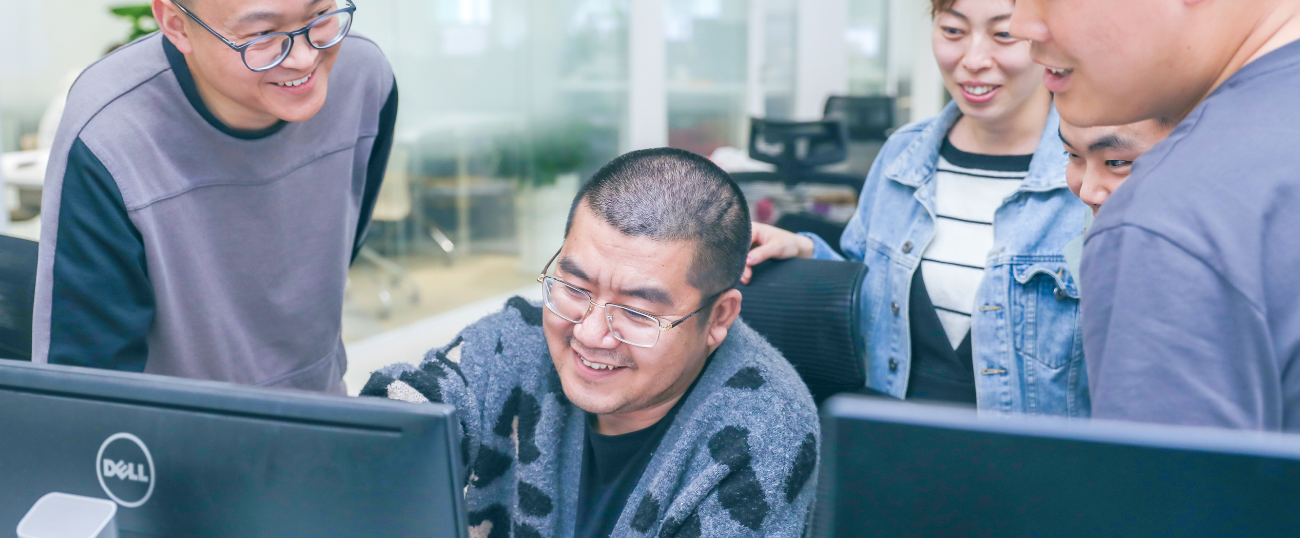 Photo of 5 Thoughtworkers gathered in an office, looking at a computer.